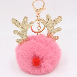 Macro detail of pink pom pom keychain with gold glitter reindeer antlers and metal clasp