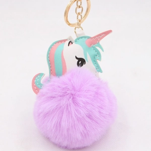 Close-up of fluffy purple unicorn keychain with golden ring and multi-colored patch