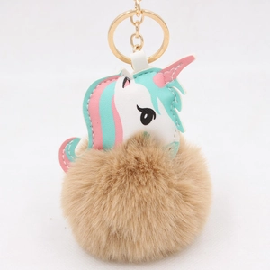 Detail of cute unicorn plush ball keychain with faux fur pom pom and gold metal link