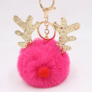 Close-up of fluffy rose red Christmas reindeer pompom keychain with gold sequins and metal clip