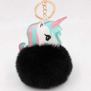 Detailed view of unicorn faux fur pompom keychain with golden metal ring and soft plush
