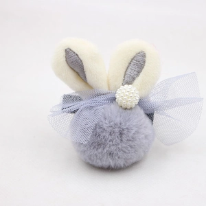 Détail d'accessoire cheveux oreilles de lapin en peluche avec pompon et perles