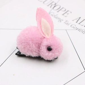 Close-up of a cute pink plush rabbit hair clip with soft ears and a black duckbill clip