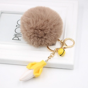 Detail of banana resin charm with brown faux fur pompom and golden horseshoe buckle