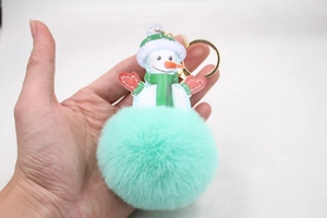 Detail view of mint green plush snowman keychain with festive scarf and golden ring