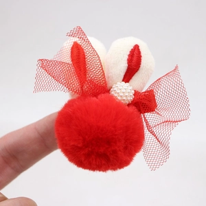 Vue détaillée d'un chouchou lapin en peluche avec pompon rouge et broderies