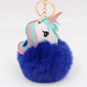 Detailed view of white leather unicorn charm with a large navy blue fluffy pom pom keychain