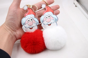 Detailed view of Santa faux fur pom pom keychain with gold clasp held by hand