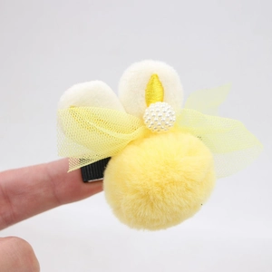 Détail de la pince à cheveux jaune en peluche avec nœud en résille et perle fille