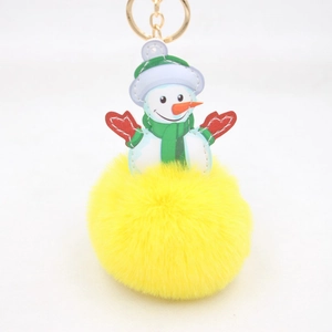 Close-up of plush Christmas snowman charm with yellow faux fur pompom and gold keychain