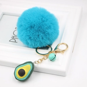 Close-up of fluffy blue plush ball keychain with silicone avocado and green bell