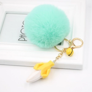 Close-up of mint green faux fur pompom keychain with yellow banana charm and gold clasp