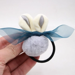 Détail d'un chouchou oreilles de lapin avec pompon en peluche et nœud en tulle bleu