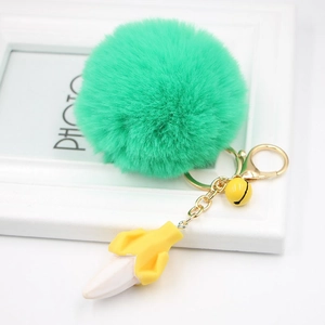 Close-up of bright green faux fur pompom keychain with resin banana charm and gold ring