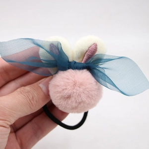Détail d'un élastique en peluche rose avec oreilles de lapin et nœud en résille bleu