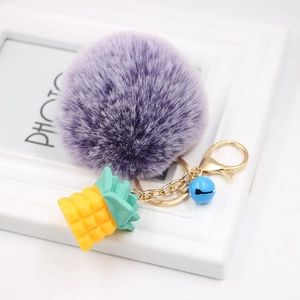 Detailed close-up of a purple fluffy pompom keychain with a yellow pineapple charm and bell