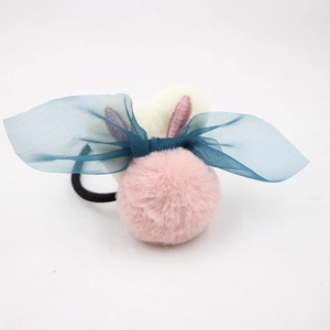 Détail d'un chouchou en peluche rose avec oreilles de lapin et nœud en maille verte