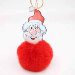 Close-up of fluffy red pompom keychain with cartoon Santa Claus pendant and gold ring