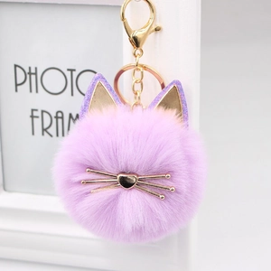Detail of a purple plush cat head keychain with glitter ears and golden heart-shaped nose