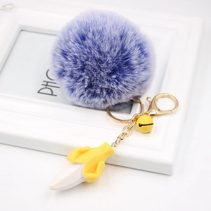 Close-up of fluffy purple pompom keychain with banana resin charm and golden hardware