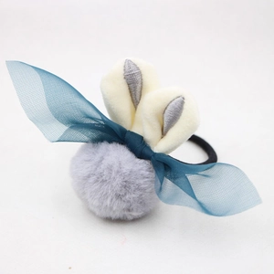 Détail d'un chouchou lapin en peluche avec pompon gris et nœud en résille bleu
