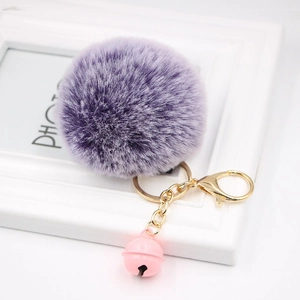 Detailed view of a purple faux fur keychain with a golden ring and pink bell attachment