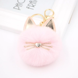Detailed view of pink fluffy cat pom pom keychain with gold cat ears and whiskers charm