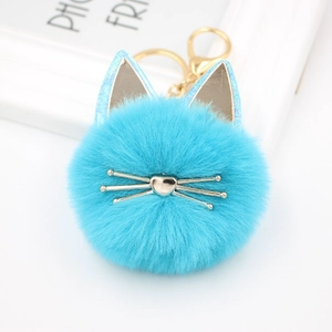 Macro shot of fluffy blue cat plush keychain with gold whiskers and metallic hardware