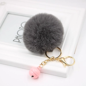 Detailed macro view of dark grey faux fur keychain with golden clasp and pink bell