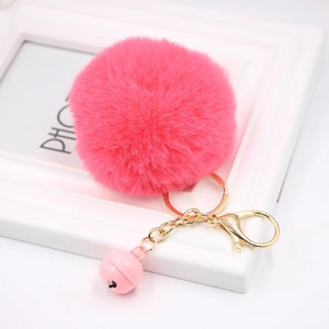 Detailed macro view of vibrant rose pink faux fur pompom keychain with golden bell