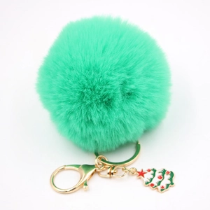 Gros plan du porte-clés pompon vert menthe avec un pendentif d'arbre de Noël doré