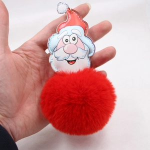 Detail of red faux fur pompom keychain with Santa Claus charm and festive stitching