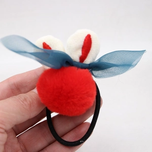 Détail d'un élastique lapin en peluche avec pompons rouges et nœud papillon en maille bleue