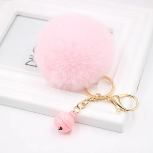 Pink faux rabbit fur pom pom keychain with golden bell and metal clip on white background