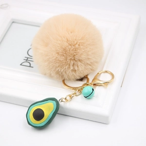Detail of avocado plush keychain with khaki fur ball and green resin charm on golden clasp