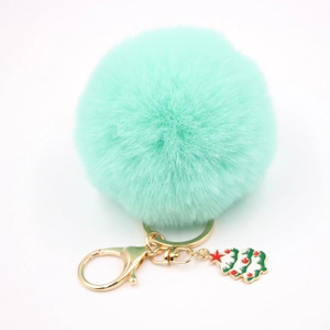 Détail d'un porte-clés pompon vert menthe avec un pendentif sapin de Noël doré