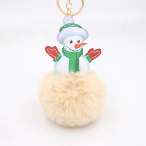 Detailed close-up of fluffy snowman pompom keychain with golden metal clasp for bags