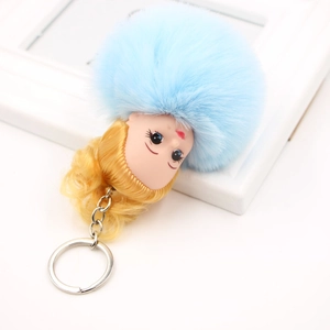 Gros plan d'un porte-clés pompon bleu ciel avec tête de poupée et anneau argenté