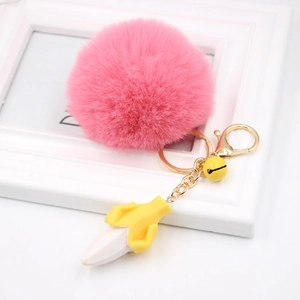 Close-up of pink faux fur pompom keychain with a yellow banana charm and gold lobster clasp