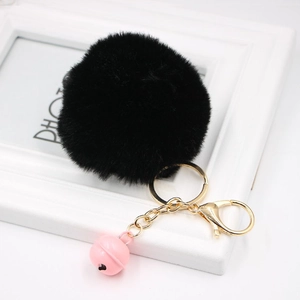 Close-up of black faux fur pom pom keychain with gold lobster clasp and pink bell charm