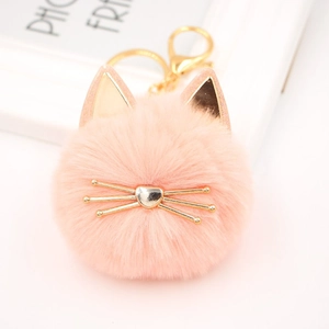 Close-up of pink plush cat keychain with golden metal whiskers and heart-shaped nose