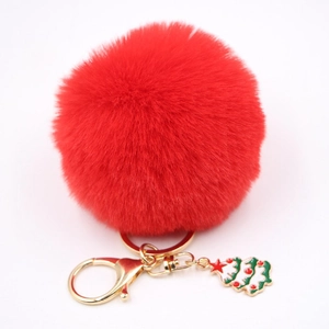 Détail du porte-clés pompon rouge avec fermoir doré et breloque sapin de Noël émaillé