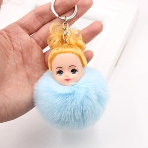 Gros plan sur un porte-clés pompon bleu clair duveteux avec tête de poupée mignonne