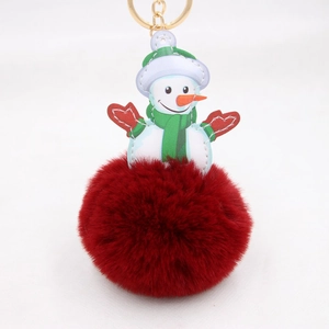 Detail of red faux fur pompom snowman keychain with golden metal clasp and green scarf