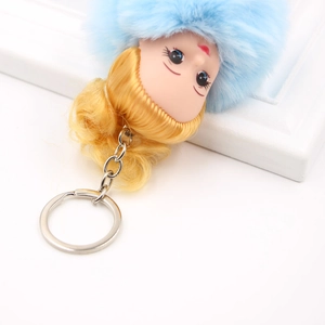 Porte-clés poupée endormie avec pompon bleu en fausse fourrure et boucles dorées