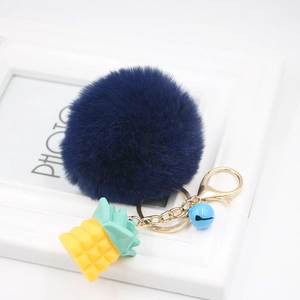 Detail of blue plush ball keychain with yellow resin pineapple and gold metal lobster clasp