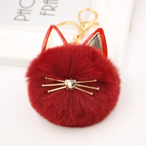 Close-up of deep red plush cat keychain with golden whiskers and metal clasp