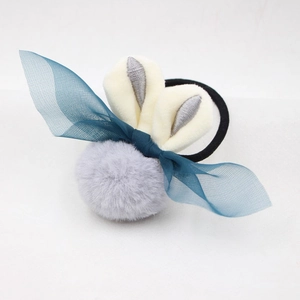 Détail de l'élastique à cheveux lapin en peluche avec pompon et nœud en gaze bleue