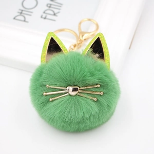 Macro shot of green plush cat keychain with golden heart nose and whiskers detail
