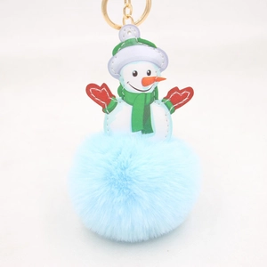 Close-up of fluffy blue snowman pompom keychain with green hat and gold ring